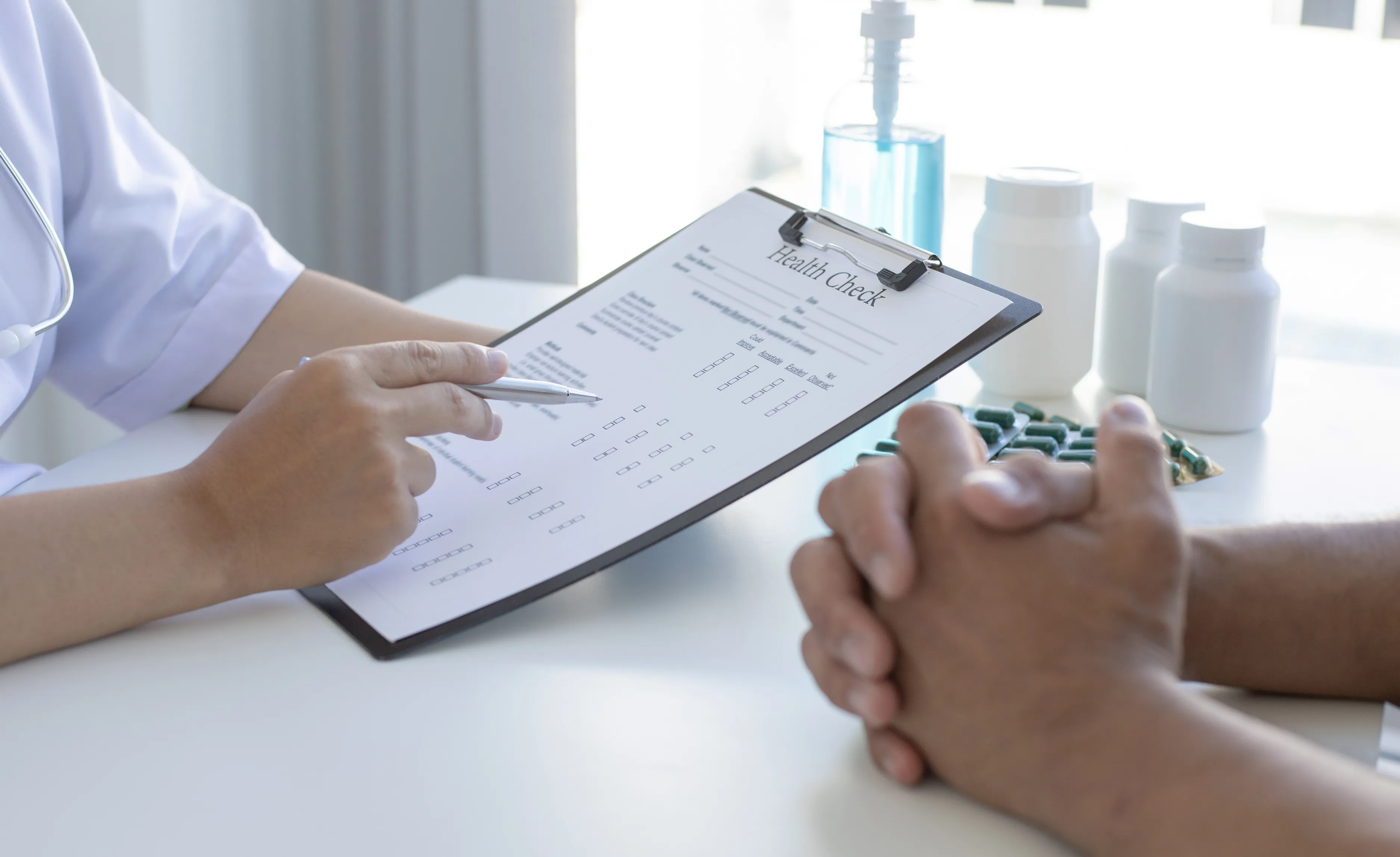 A healthcare professional reviewing a health check form with a patient seated opposite.